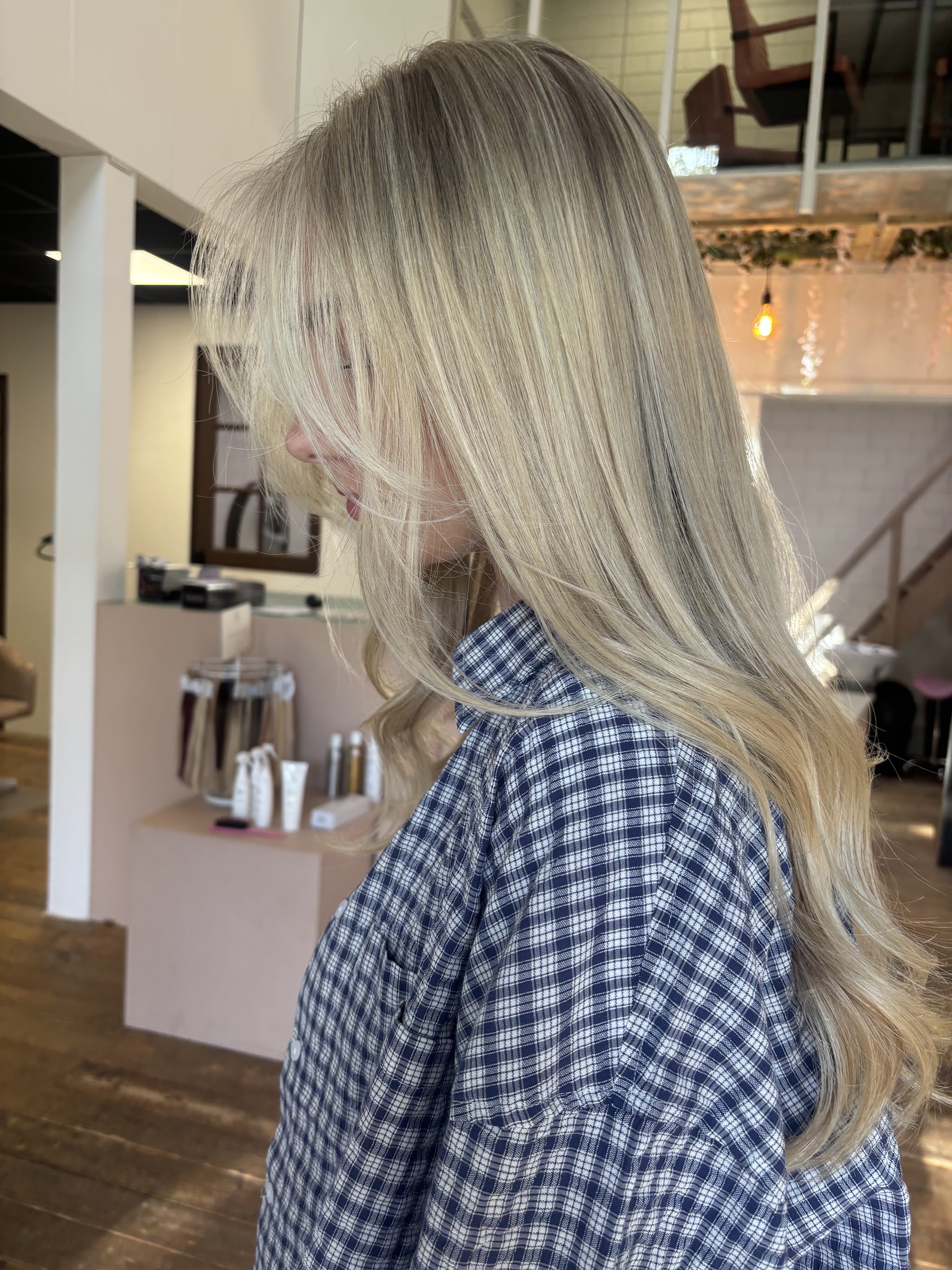 IJsblond haar in de salon van Studio M.E.S, met het productschap en de warme lampen op de achtergrond